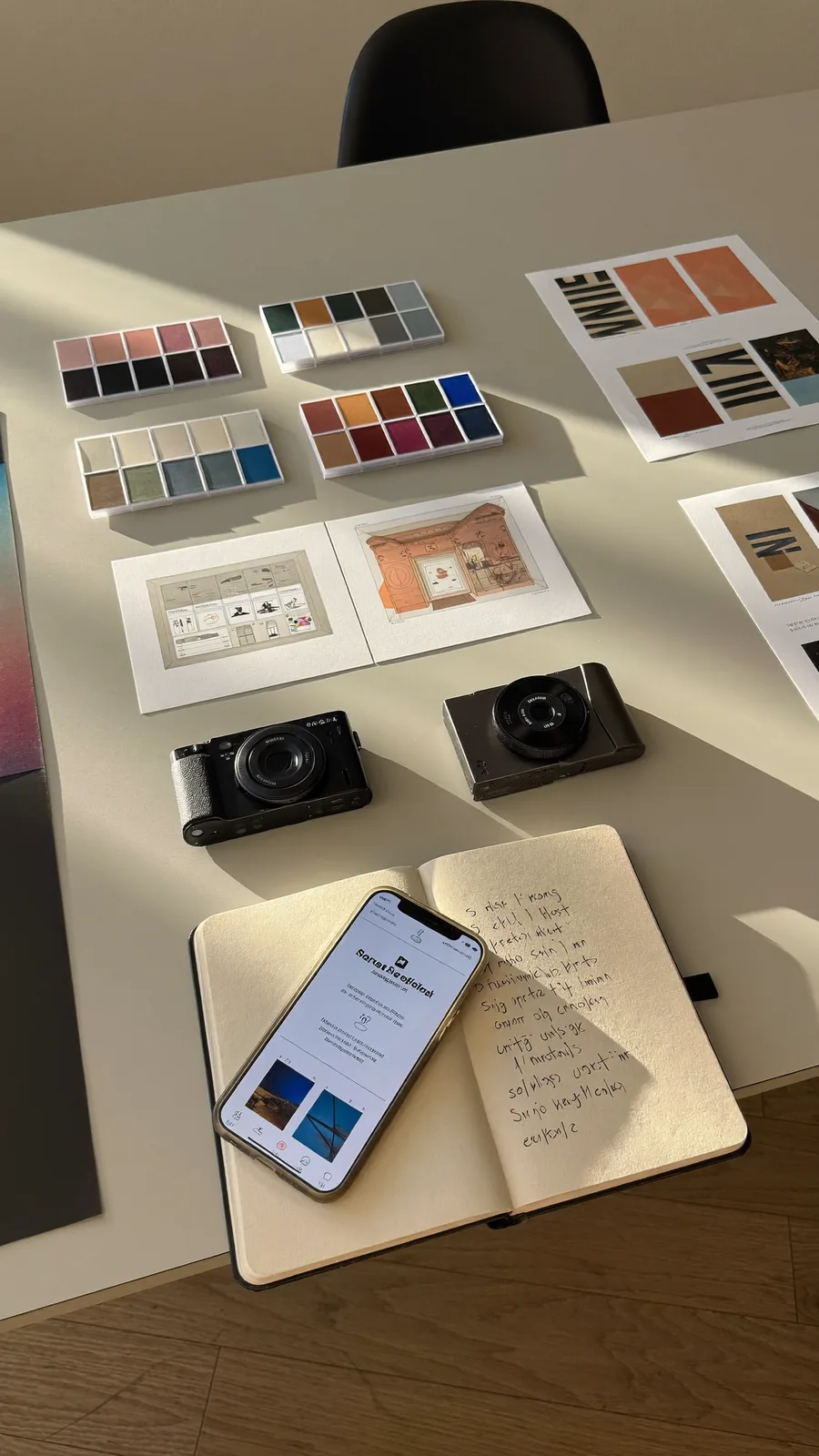 Printed brand identity boards, color palettes, a camera and notes arranged on a table.